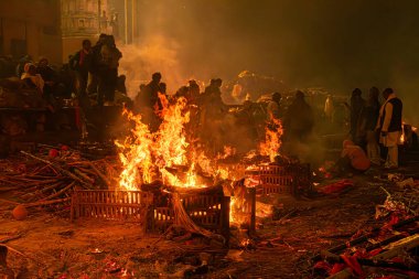 Varanasi, Uttar Pradesh, Hindistan, 28 Ocak 2024: Loş gökyüzünün altında, Manikarnika Ghat 'taki ateş, gelenek, inanç ve şehrin ölümden sonraki yaşamla ebedi bağlantısı.