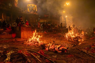 Varanasi, Uttar Pradesh, Hindistan, 28 Ocak 2024: Alacakaranlıkta, Manikarnika Ghat 'ın alevleri durmaksızın yanarak, Varanasi' nin göbeğindeki ayrılan ruhların son yolculuğunu aydınlatıyor..