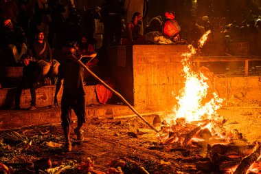 Varanasi, Uttar Pradesh, Hindistan, 28 Ocak 2024: Gece parıltısı, titreyen közlerin yükseldiği, ruhları özgürlüğe taşıyan Manikarnika Ghat 'taki yakma ateşiyle birleşiyor.