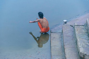 Varanasi, Uttar Pradesh, Hindistan, 29 Ocak 2024: Bir adam Ganga 'da sabah duşundan önce sabah ayinlerini gerçekleştiriyor..