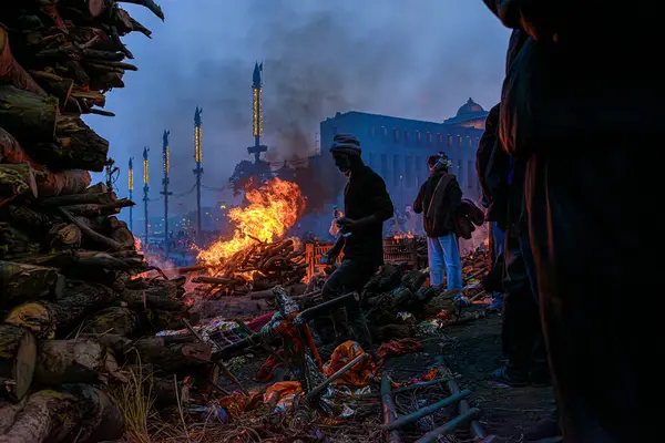 Varanasi, Uttar Pradesh, Hindistan, 26 Ocak 2024: Manikarnika Ghat 'in kaotik telaşı içinde, işçiler her türlü ayinin tamamlandığından emin olmak için dumanın içinde hareket ediyorlar, çünkü yangın hiç bitmiyor..