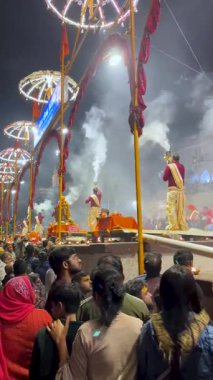 Varanasi, Uttar Pradesh, Hindistan, 28 Ocak 2024: Varanasi 'de rahipler Ganga Aarti' yi Dashashwamedh Ghat 'ta, kıvılcımlı alevler, ritmik çanlar ve parlayan kutsal nehirde icra ederken ilahi bir akşam.