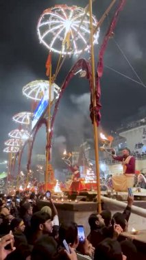 Varanasi, Uttar Pradesh, Hindistan, 28 Ocak 2024: Geleneksel giysiler içindeki rahipler, Dashashwamedh Ghat 'ta Ganga Aarti' yi sahnelerken, kutsal nehir gökyüzünün altında parlarken, büyük pirinç lambaları sallıyorlar..