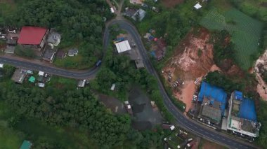 Yüksek bir drone atışı Meghalayaların dolambaçlı yollarını yakalıyor, araçlar verimli yeşil manzaralarla çevrili düz virajlarda gezinirken..