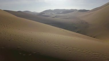 Çöl manzarasında dalgalanan kum tepeciklerinde ayak izleri