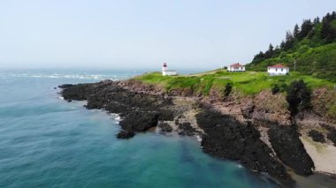 Sakin bir okyanusa bakan kayalık bir sahilde, resim gibi bir deniz fenerinin havadan görünüşü..