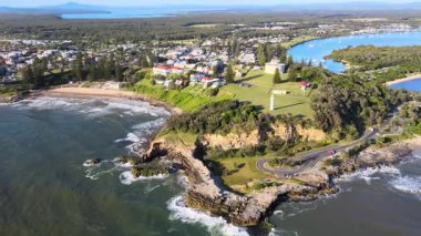 Deniz feneri, plaj ve okyanus dalgaları olan muhteşem bir sahil kasabası manzarası..