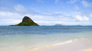 Parçalı bulutlu bir gökyüzünün altında volkanik adaların bulunduğu Oahu 'nun kıyı şeridinin huzurlu manzarası.