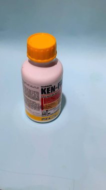 Mavi arka planda bir şişe böcek ilacı.