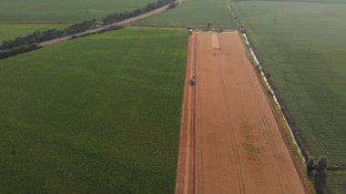 Ağır hasat makinelerinin ve traktörlerin yeni hasat edilmiş buğday tarlasında senkronize hareketlerini gösteren erik görüntüler modern tarımın gücünü ve ritmini gözler önüne seriyor.