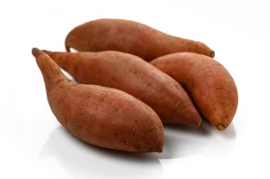 Taze biçilmiş tatlı patatesler parlak ışık altında canlı renklerini ve eşsiz şekillerini sergiliyorlar..