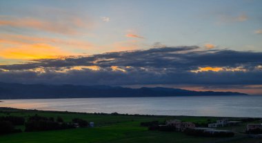 Alacakaranlık ufku canlı renklerle boyar, sakin suları aydınlatır ve sakin sahillerdeki yumuşak tepeleri..