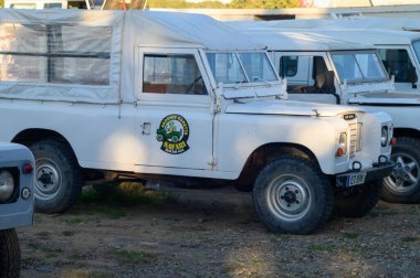 Gaziveren Kıbrıs Rum Kesimi - 19.01.2025 Klasik beyaz safari kamyonu güneşli bir açık havada diğer araçların arasında sessizce oturuyor.