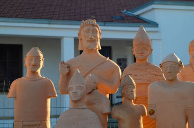 Tarihsel şahsiyetlerin heykelleri altın güneşin altında gururla durur, sanat ve zanaatkarlık sergilerler..