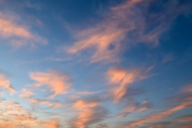 Pembe ve turuncu bulutların büyüleyici bir görüntüsü alacakaranlık gökyüzünü geceye dönüşürken dolduruyor..