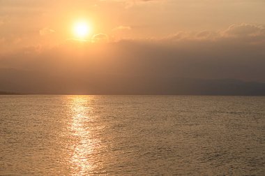 Ilık güneş ışığı sakin sulara yansıyor gün dingin bir sona yaklaşırken, güzel bir altın ufuk yaratıyor..