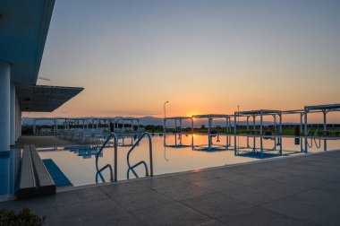 Güneş batarken, ılık parıltısı havuzun sakin suyuna çarpıcı bir yansıma yaratarak rahatlamaya yol açıyor..