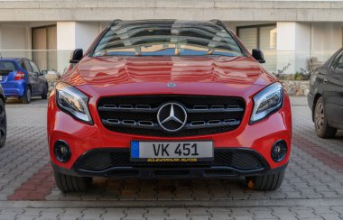 Gaziveren Kıbrıs Rum Kesimi - 30.01.2025 Çarpıcı kırmızı bir araba şık tasarımlar ve yumuşak öğleden sonra gölgeleriyle çevrili şık bir park alanında göze çarpıyor.