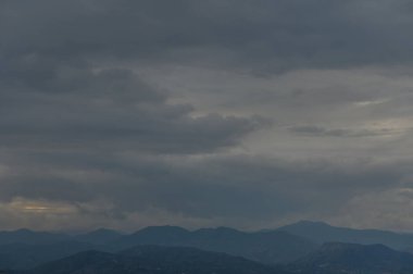 Tırtıklı dağların üzerinde dönen kara bulutlar yaklaşan fırtınadan önce sakin bir atmosfer yaratıyor..