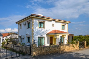 Sıcak ışık, taştan bir duvarla çevrili güzel beyaz bir evi ve sakin bir ortamda canlı bir yeşilliği yıkıyor..