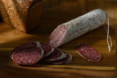 Delicious salami slices with rustic bread create a warm, inviting atmosphere perfect for a delightful meal. clipart