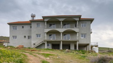 Kemerleri ve balkonları olan, kasvetli bir gökyüzünün altında yeşil tarlalarla çevrili geniş bir villa, köylü cazibesini sergiliyor..