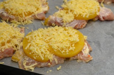 Tavuk dilimleri tatlı ananas ve dilimlenmiş peynirle kaplı, mükemmel pişirilmeyi bekliyor..