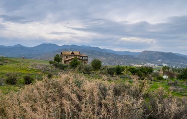 Büyüleyici bir taş ev, uzak dağların çerçevelediği yemyeşil tepelerin ve alacakaranlıkta dramatik bir gökyüzünün ortasında sessizce duruyor..