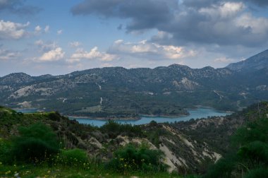 Geniş manzara dağları, parıldayan bir gölü ve öğleden sonra boyunca canlı yeşillikleri sergiliyor..