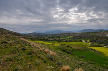 Yeşil yemyeşil tarlalar vadi boyunca uzanırken fırtına bulutları sakin bir kırsal alanda toplanıyor..