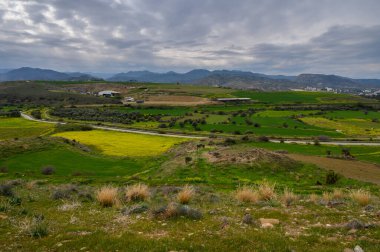 Parlak yeşil tarlalarla bezenmiş yuvarlanan tepeler ve kasvetli bir gökyüzünün altında açan sarı alanlar huzuru davet ediyor..
