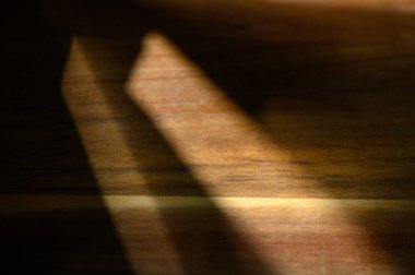 Öğleden sonra ışıklarının yumuşaklığı, ahşap bir yüzeyi nazikçe aydınlatarak, dokusunu geliştiren hassas gölgeler oluşturur..