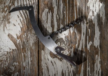 A beautifully crafted corkscrew lies elegantly on weathered wood, evoking a sense of warmth and nostalgia. clipart