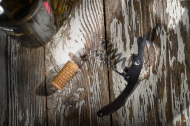 Kırsal ahşap masa bir mantar, bir tirbuşon ve bir şişe tutuyor. Hepsi sevinçle dolu bir kutlama anına hazır..