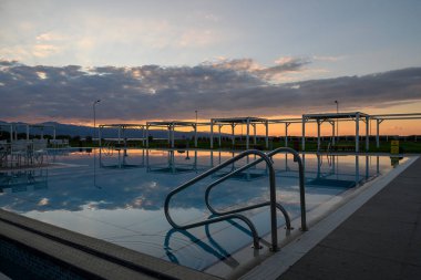 Güneş batarken, altın renkler havuzun sakin yüzeyinde dans ederek rahatlamak için huzurlu bir vaha oluşturuyor..