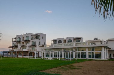 Çağdaş bir bina, verimli yeşillik ve sakin çevreyle harmanlanmış günbatımına karşı zarifçe ayakta duruyor..