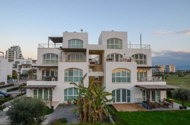 Modern konut binası, altın saat boyunca canlı bir gökyüzünün altında yemyeşil ile çevrili duruyor..