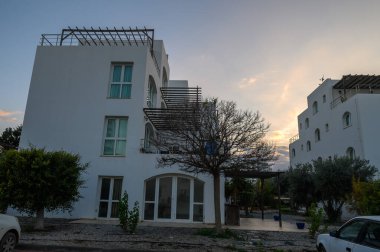 Göz kamaştırıcı beyaz binalar yemyeşil alanların arasından bakıyor. Güneş ufkun altına batıyor ve sakin bir atmosfer yaratıyor..