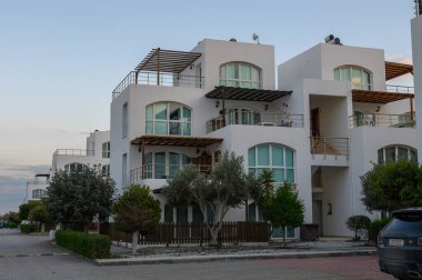 Ağaçların arasına yerleşmiş sofistike evler, sakin bir alacakaranlık gökyüzü altında mimari tasarım sergiliyorlar..