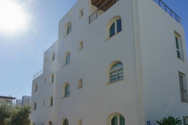 Öğle güneşinin altında eşsiz kemerli pencereler ve sakin bir atmosferi olan güzel bir bina duruyor..