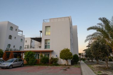 Zarif beyaz binalar alacakaranlığın yumuşak parıltısında güneşleniyorlar, modern tasarım ve sakin bir çevre sergiliyorlar..