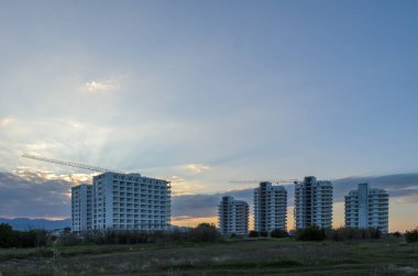 Yeni gökdelenler renkli bir günbatımına karşı yükseliyor, inşaat vinçleri kentsel ufuk çizgisini yükseltiyor.