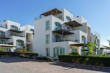 Göz kamaştırıcı bir villa berrak gökyüzünün altında duruyor zarif mimari ve canlı yeşillik sergiliyor..