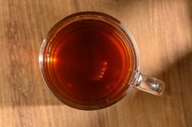 Dumanı tüten bir fincan çay, yumuşak bir öğleden sonra ışığında parlayan, tahtadan bir masanın üzerinde huzur içinde oturur..