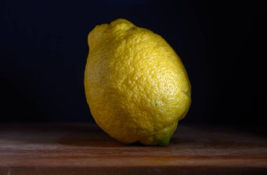 Kaba ahşap bir tahtanın üzerindeki parlak bir limon koyu arkaplanla çok güzel zıtlaşır ve dokusunu renklendirir..