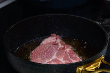 Sulu bir biftek, dökme demir bir tavada kızarıyor. Sıcak bir mutfak atmosferinde lezzetli kokular yayıyor..