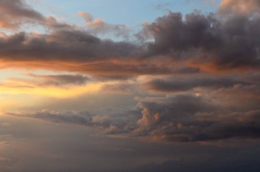 Bulutlar akşam gökyüzünde zarifçe yuvarlanırken, altın renkler derin mavilerle harmanlanır ve nefes kesici bir atmosfer yaratır..