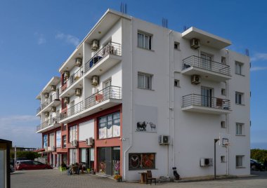 Modern mimari açık mavi gökyüzü altında renkli bir cephe ve davetkar balkonlar sergiliyor..