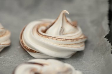 Yumuşak kremalı krema kıvrımları, karamelize kenarları parşömen üzerinde dinleniyor, sıcak bir mutfakta tatlı işçiliği vurgulanıyor..