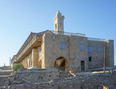 Kırsal bir taş yapı, bir yamaçta gururla durur, sıcak altın güneş ışığıyla yıkanır ve doğayla çevrilidir..